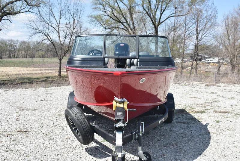 Slide: The Image of 2025 Lund 1775 Impact XS Sport boat on trailer, red exterior, parked outdoors. - 2