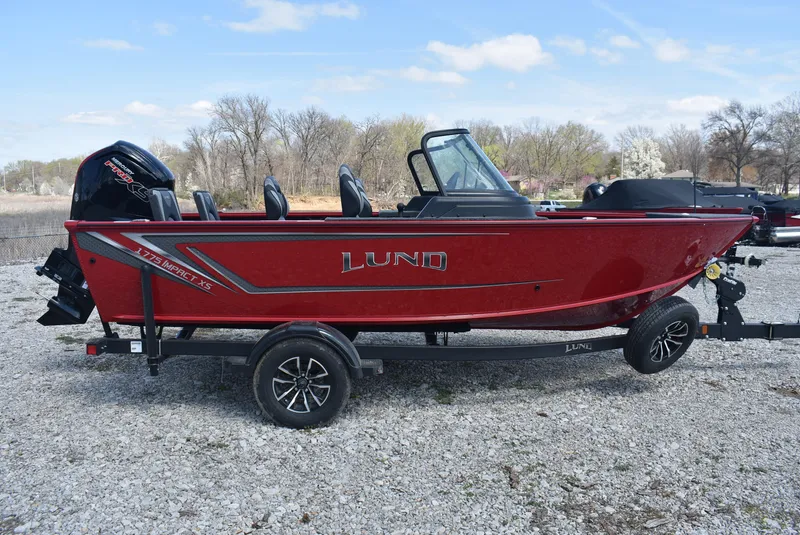 Slide: The Image of 2025 Lund 1775 Impact XS Sport boat, red, on trailer, parked on gravel. - 4