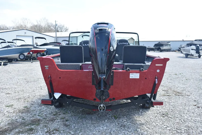 Slide: The Image of 2025 Lund 1775 Impact XS Sport boat, rear view, red exterior, parked on gravel. - 5