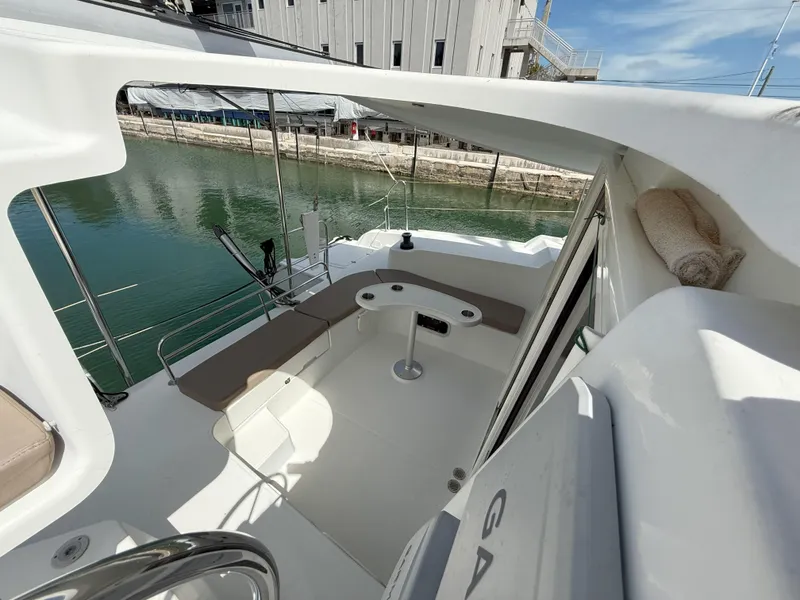 Slide: The Image of 2014 Fountaine Pajot Mahe 36 Evolution yacht cockpit with seating and table, docked by water. - 25