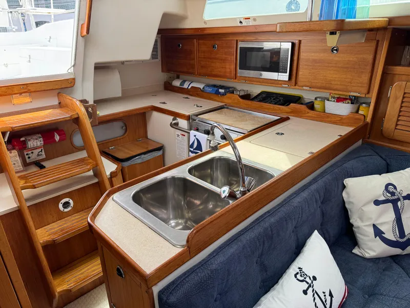 Slide: The Image of Interior of a 1999 Catalina 36 Mk II sailboat, featuring a kitchen with a sink and microwave. - 16