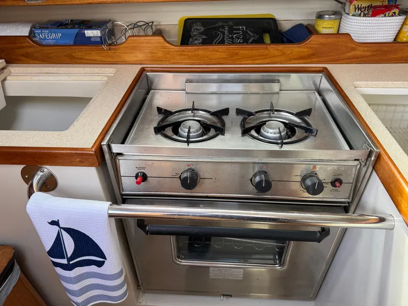Slide: The Image of 1999 Catalina 36 Mk II yacht kitchen with stainless steel stove and nautical-themed towel. - 21