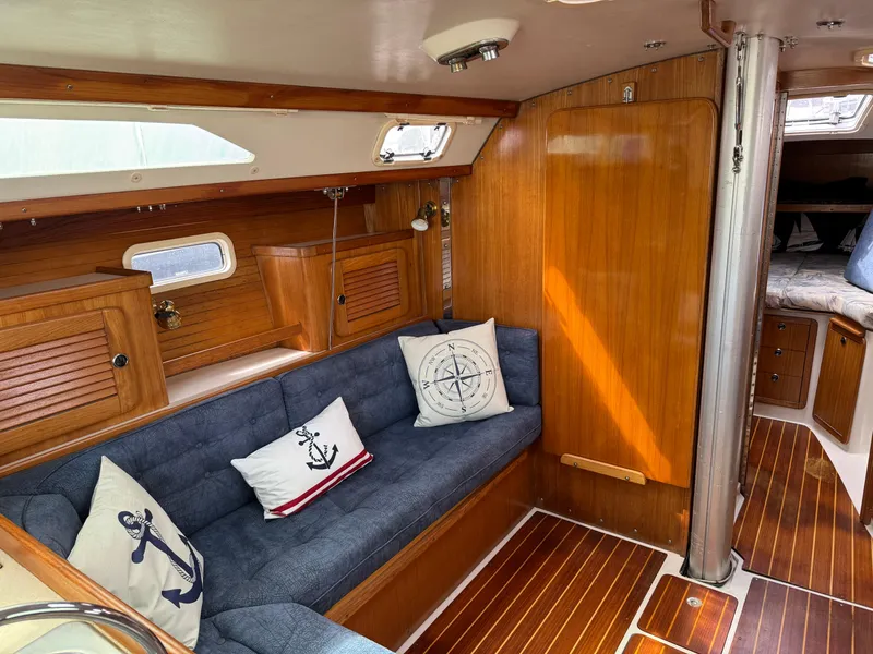 Slide: The Image of 1999 Catalina 36 Mk II interior with wooden finish, blue sofa, nautical-themed pillows. - 29