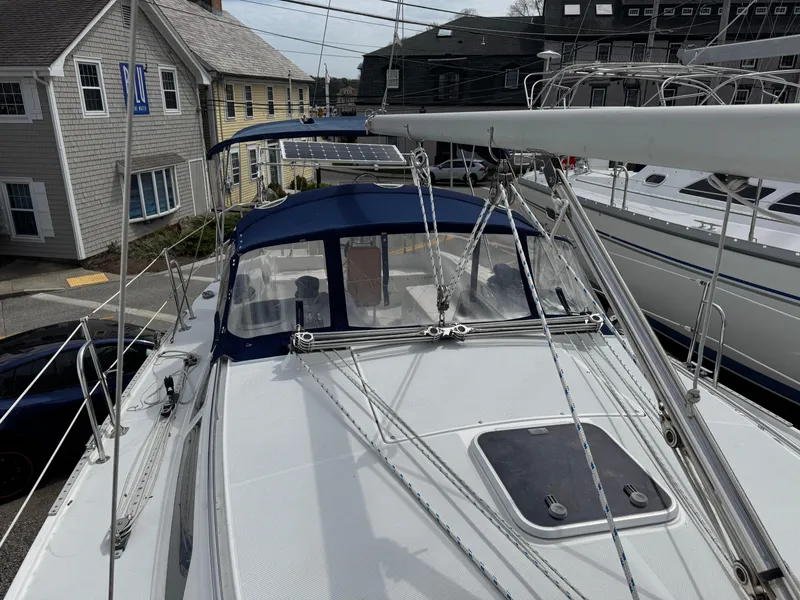 Slide: The Image of 1999 Catalina 36 Mk II sailboat with blue canopy, docked near coastal buildings. - 3