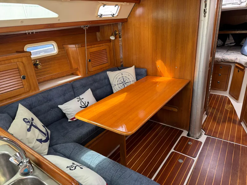 Slide: The Image of 1999 Catalina 36 Mk II yacht interior with wooden table, blue seating, and nautical-themed pillows. - 30