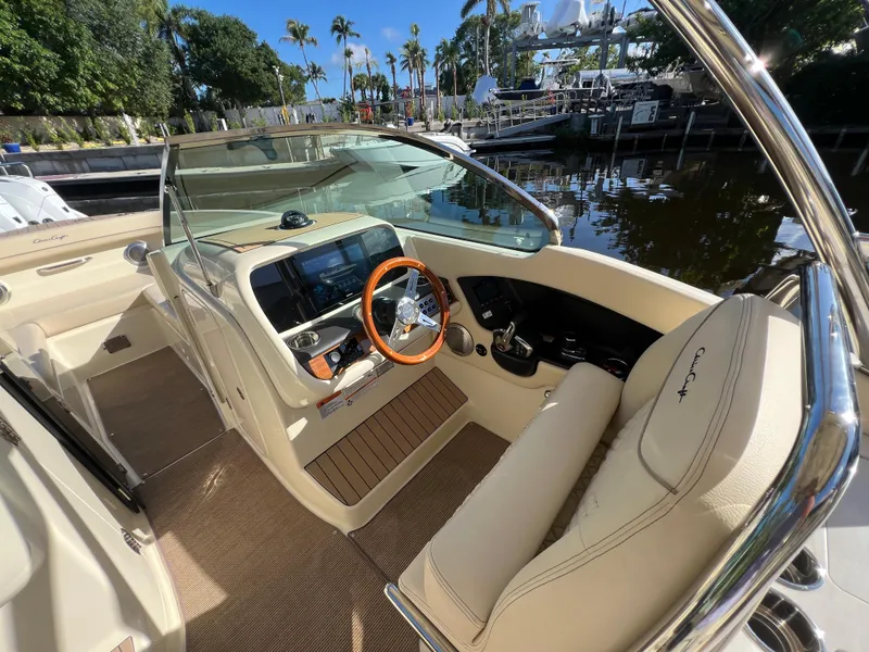 Slide: The Image of 2025 Chris-Craft Calypso 28 boat interior with steering wheel and dashboard, docked by palm trees. - 13