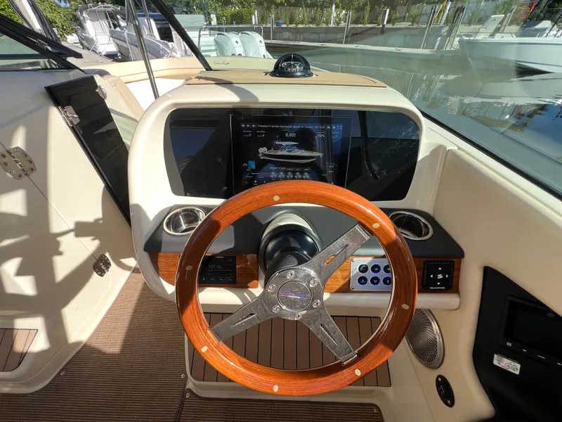 Slide: The Image of 2025 Chris-Craft Calypso 28 helm with wooden steering wheel and modern dashboard display. - 14