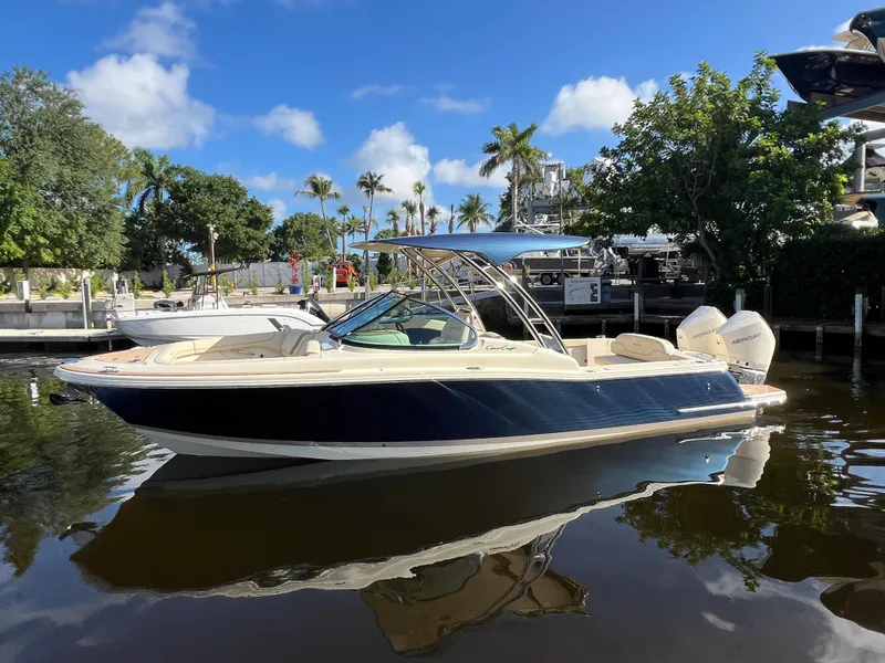 Slide: The Image of 2025 Chris-Craft Calypso 28 boat docked on a sunny day, surrounded by palm trees. - 2