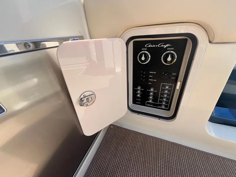 Slide: The Image of 2025 Chris-Craft Calypso 28 control panel with open access door, showcasing switches and dials. - 21