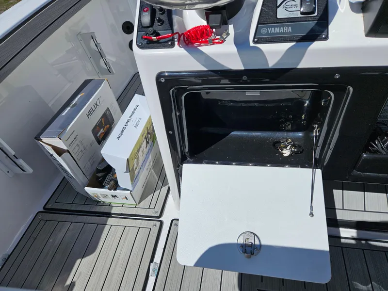 Slide: The Image of 2021 Yamaha Boats 210 FSH Deluxe interior with storage compartment and accessories. - 16