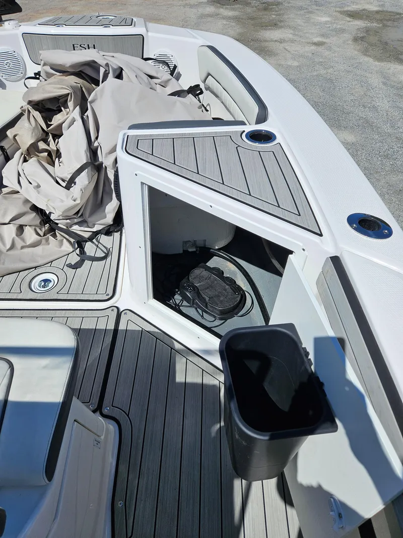 Slide: The Image of 2021 Yamaha Boats 210 FSH Deluxe deck with storage compartment and seating area. - 17