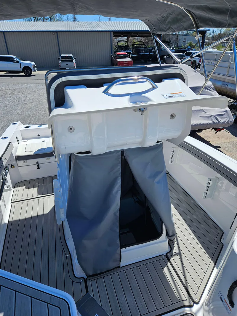 Slide: The Image of 2021 Yamaha Boats 210 FSH Deluxe interior with storage compartment open, showcasing deck and seating. - 21