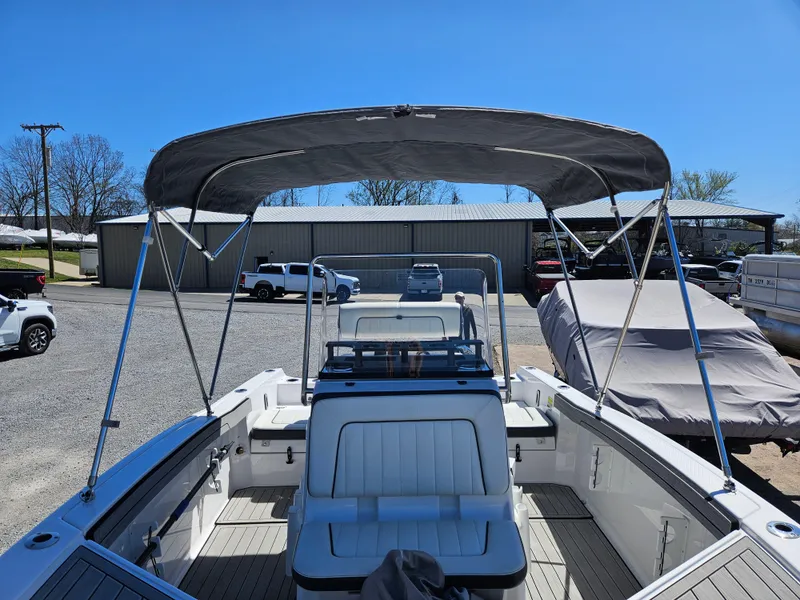 Slide: The Image of 2021 Yamaha Boats 210 FSH Deluxe with canopy, parked outdoors under clear blue sky. - 24