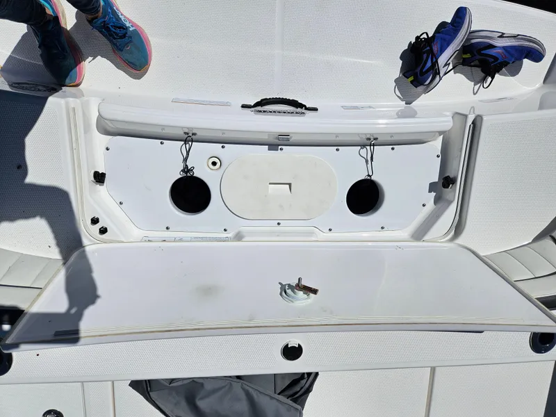 Slide: The Image of 2021 Yamaha Boats 210 FSH Deluxe deck with storage compartment and shoes visible. - 30