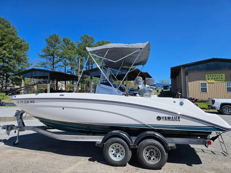 Slide: The Image of 2021 Yamaha Boats 210 FSH Deluxe on trailer, parked outdoors under clear blue sky. - 32