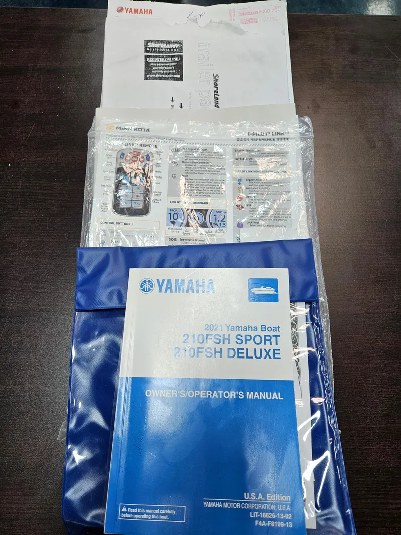 Slide: The Image of 2021 Yamaha Boats 210 FSH Deluxe owner's manual on a table. - 36