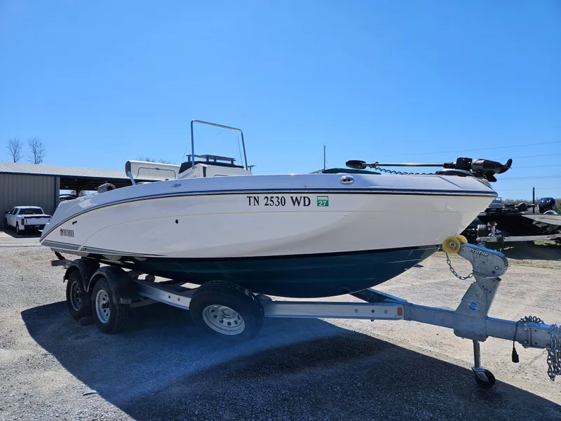 Slide: The Image of 2021 Yamaha Boats 210 FSH Deluxe on trailer, parked outdoors under clear blue sky. - 4