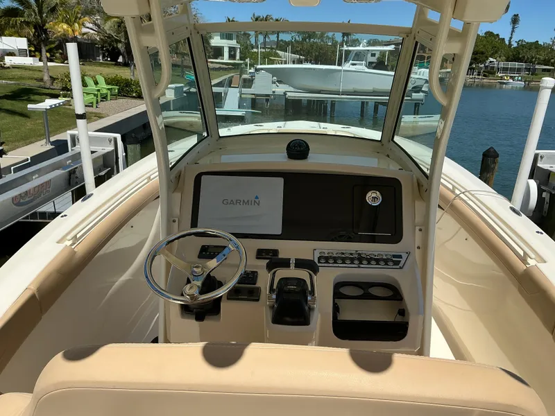 Slide: The Image of 2019 Scout 275 LXF boat cockpit with Garmin navigation system, docked by a serene waterfront. - 10