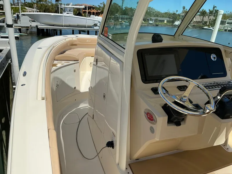 Slide: The Image of 2019 Scout 275 LXF boat interior with steering wheel and dashboard, docked by the water. - 17