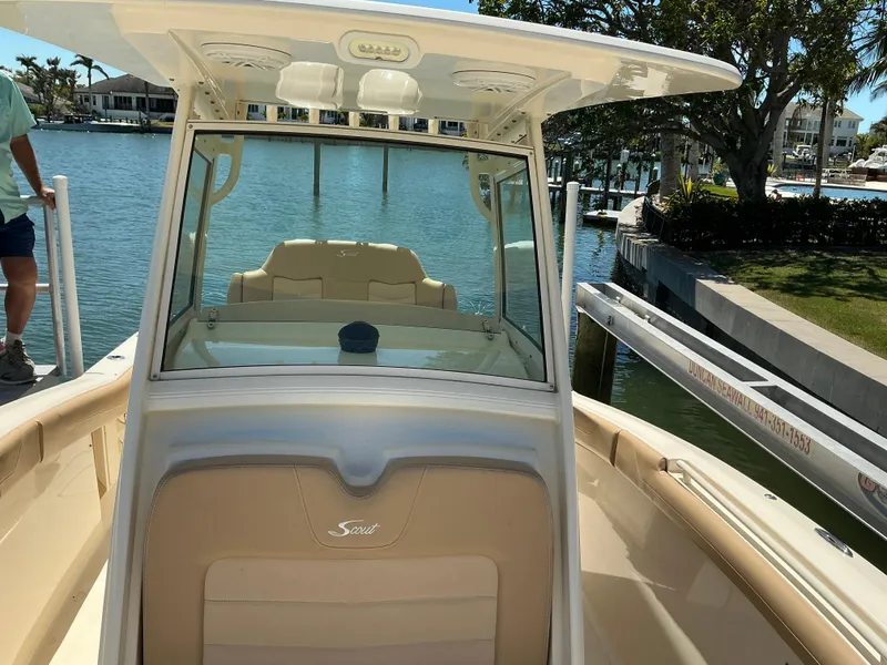 Slide: The Image of 2019 Scout 275 LXF boat docked by waterfront homes, showcasing sleek design and spacious deck. - 23