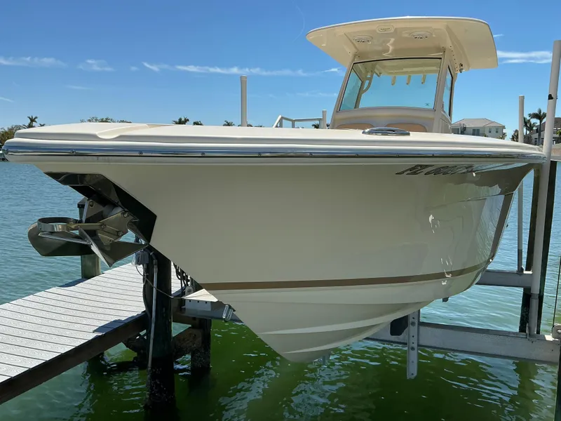 Slide: The Image of 2019 Scout 275 LXF boat on lift, docked by waterfront, under clear blue sky. - 3