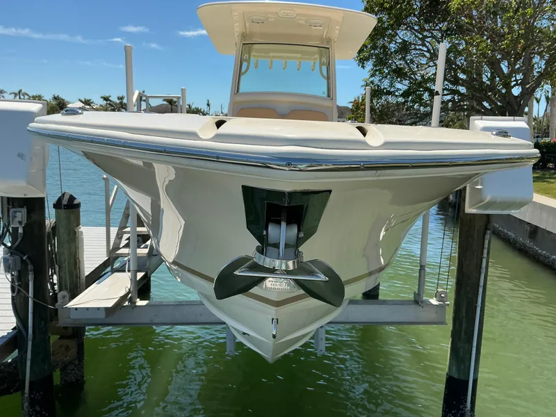 Slide: The Image of 2019 Scout 275 LXF boat on lift, docked by green water, sunny day. - 4