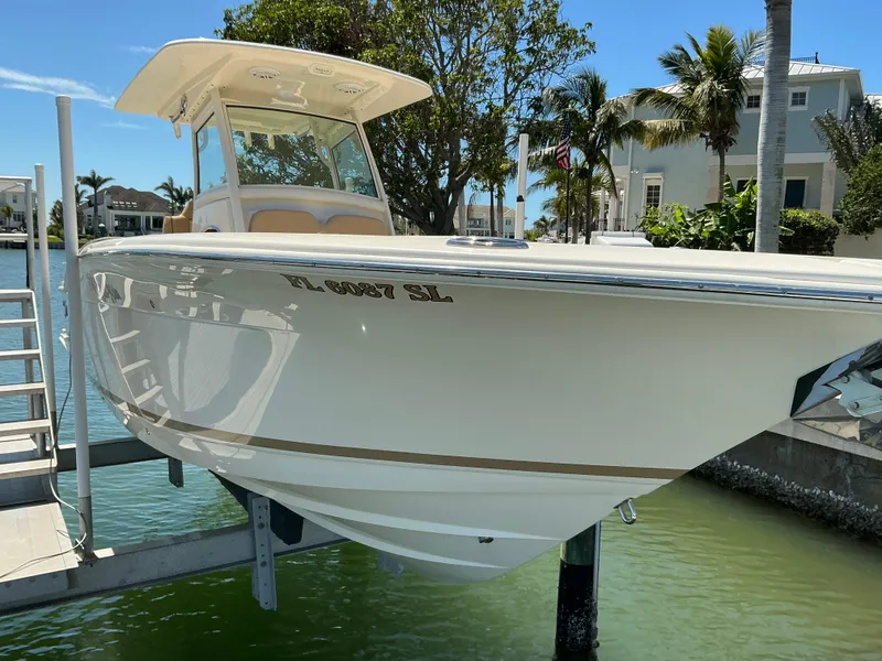 Slide: The Image of 2019 Scout 275 LXF boat docked near waterfront homes, sunny day. - 5