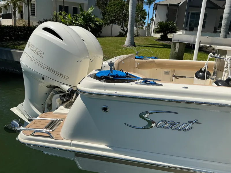 Slide: The Image of 2019 Scout 275 LXF boat with outboard motor, docked near waterfront homes. - 6