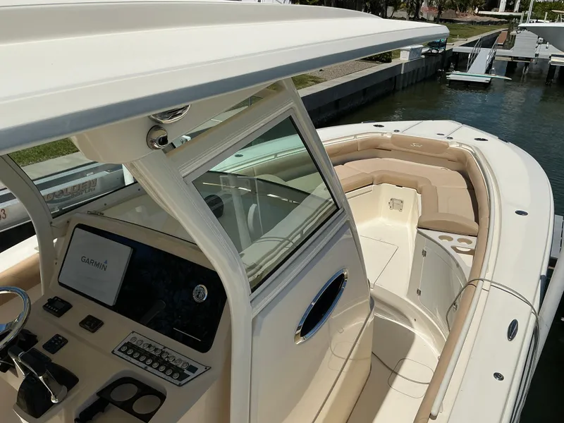 Slide: The Image of 2019 Scout 275 LXF boat with beige seating and modern dashboard, docked by the water. - 9