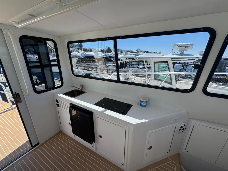 Slide: The Image of Interior view of 2020 Cape Powercat 3500 PH with kitchenette and marina backdrop. - 18