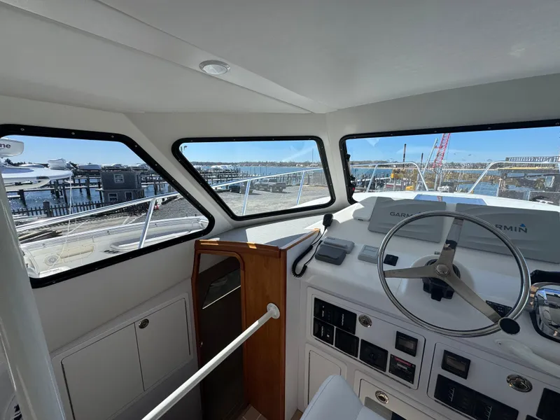 Slide: The Image of Interior view of 2020 Cape Powercat 3500 PH boat helm with marina background. - 23