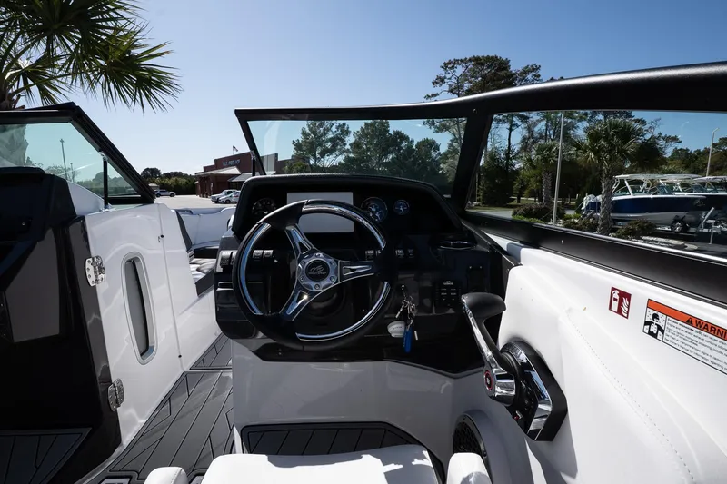 Slide: The Image of 2025 Monterey M-65 boat cockpit with steering wheel and controls, surrounded by lush greenery. - 19