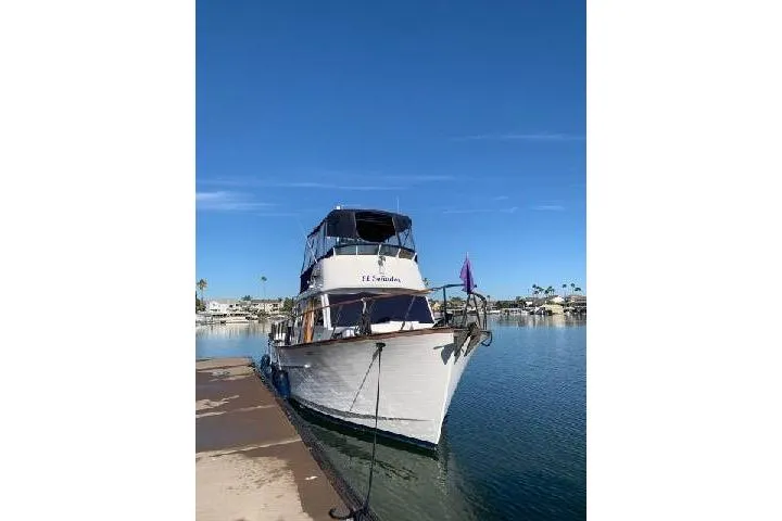 The Image of 1982 Monk 36 boat docked on calm water under clear blue sky. - 0