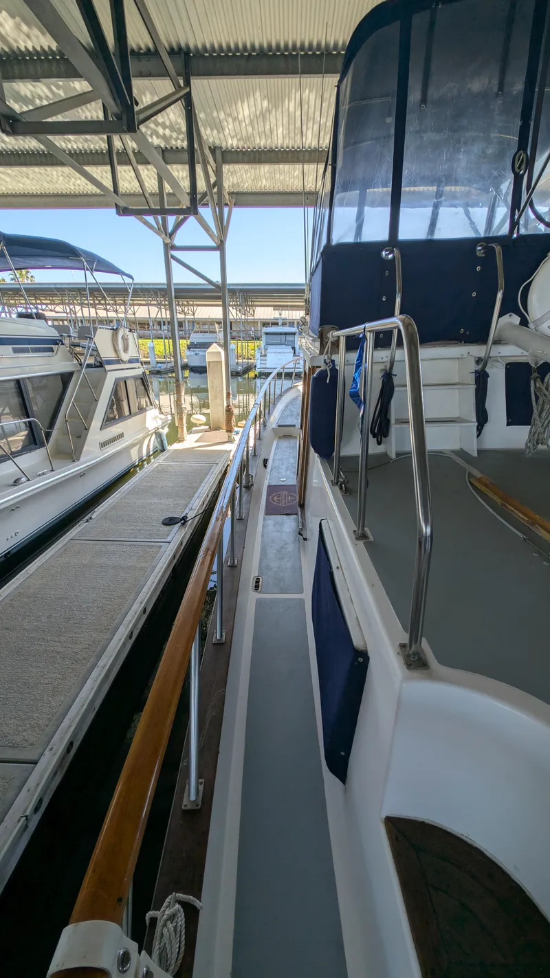 Slide: The Image of 1982 Monk 36 yacht docked in a marina, showcasing side deck and railing. - 10