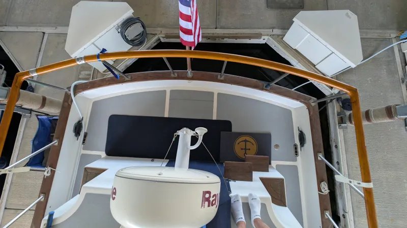 Slide: The Image of 1982 Monk 36 boat deck with American flag, wooden railings, and nautical equipment. - 12