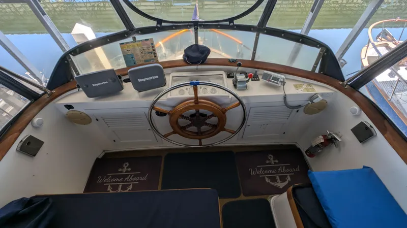 Slide: The Image of 1982 Monk 36 boat cockpit with wooden steering wheel, navigation equipment, and "Welcome Aboard" mats. - 19