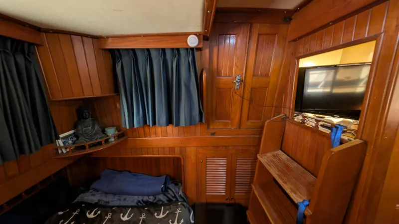 Slide: The Image of Cozy wooden interior of 1982 Monk 36 boat with bed, shelves, and curtains. - 36