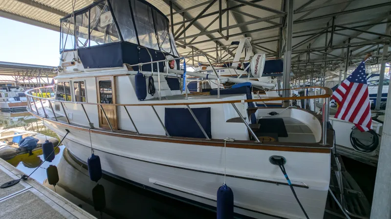 Slide: The Image of 1982 Monk 36 yacht docked in marina, featuring American flag and covered upper deck. - 4