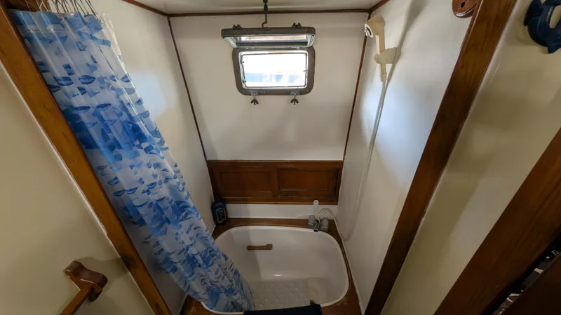 Slide: The Image of Small boat bathroom with shower, blue curtain, and wooden accents, Monk 36, 1982 model. - 43
