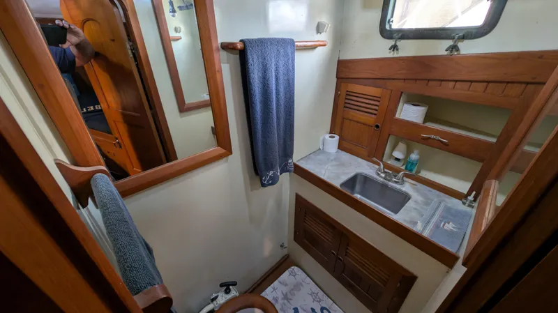Slide: The Image of 1982 Monk 36 yacht bathroom with wooden cabinetry, sink, mirror, and towel. - 48