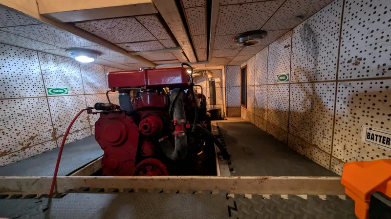 Slide: The Image of Engine room of a 1982 Monk 36 boat, featuring a red engine and perforated walls. - 50