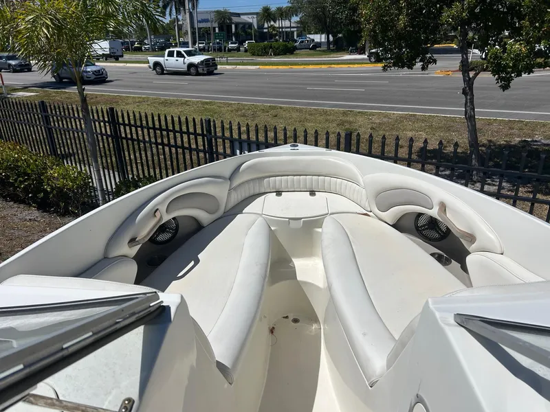 Slide: The Image of 2003 Stingray 240 LR boat with white seating, parked near a road and fence. - 21