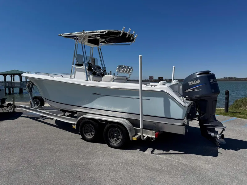 Slide: The Image of 2009 Sea Hunt Triton 220 boat on trailer with Yamaha outboard motor, parked near water. - 2