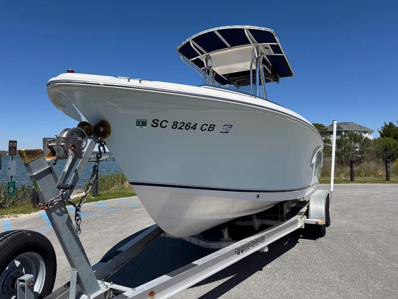 Slide: The Image of 2009 Sea Hunt Triton 220 boat on trailer, parked near water under clear blue sky. - 6