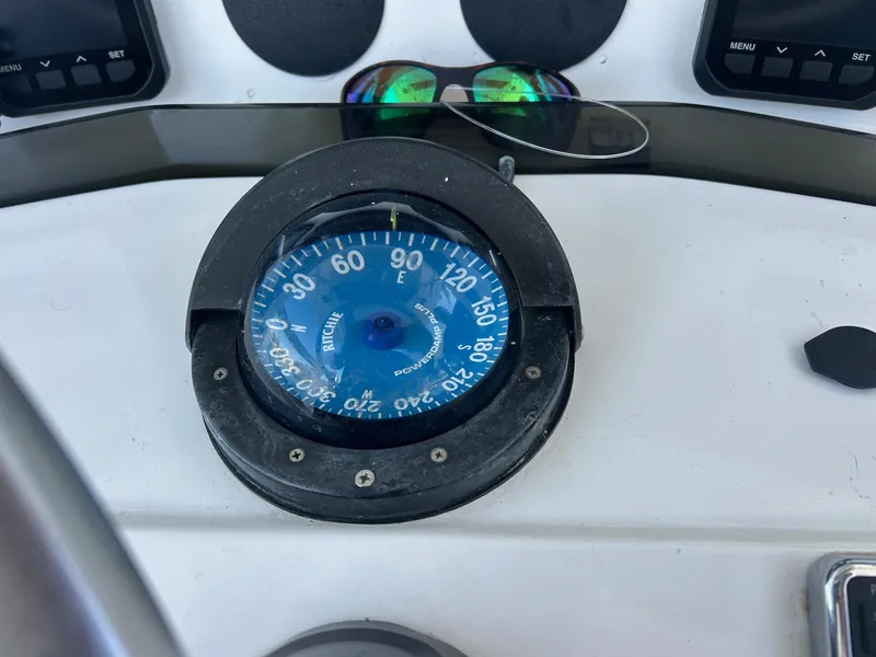 Slide: The Image of Compass on 2002 Venture 34 Center Console boat dashboard with sunglasses nearby. - 18