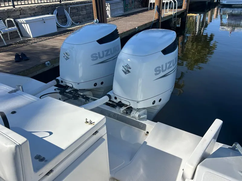 Slide: The Image of Twin Suzuki outboard motors on a 2002 Venture 34 Center Console boat at a dock. - 2