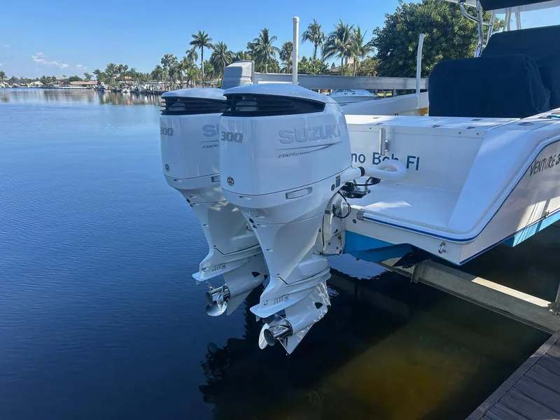 Slide: The Image of Twin Suzuki outboard motors on a 2002 Venture 34 Center Console boat docked by palm trees. - 3
