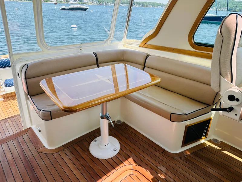 Slide: The Image of 2008 Sabre 42 Hardtop Express interior with wooden table, cushioned seating, and scenic water view. - 16