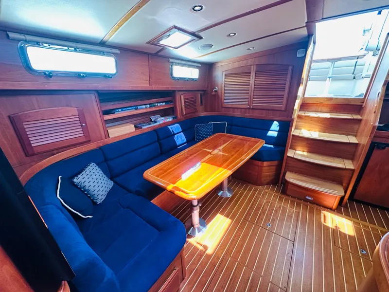 Slide: The Image of 2008 Sabre 42 Hardtop Express interior with wooden table, blue seating, and stairs. - 26