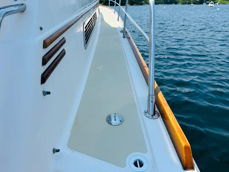 Slide: The Image of 2008 Sabre 42 Hardtop Express yacht deck with wooden railings on calm water. - 6